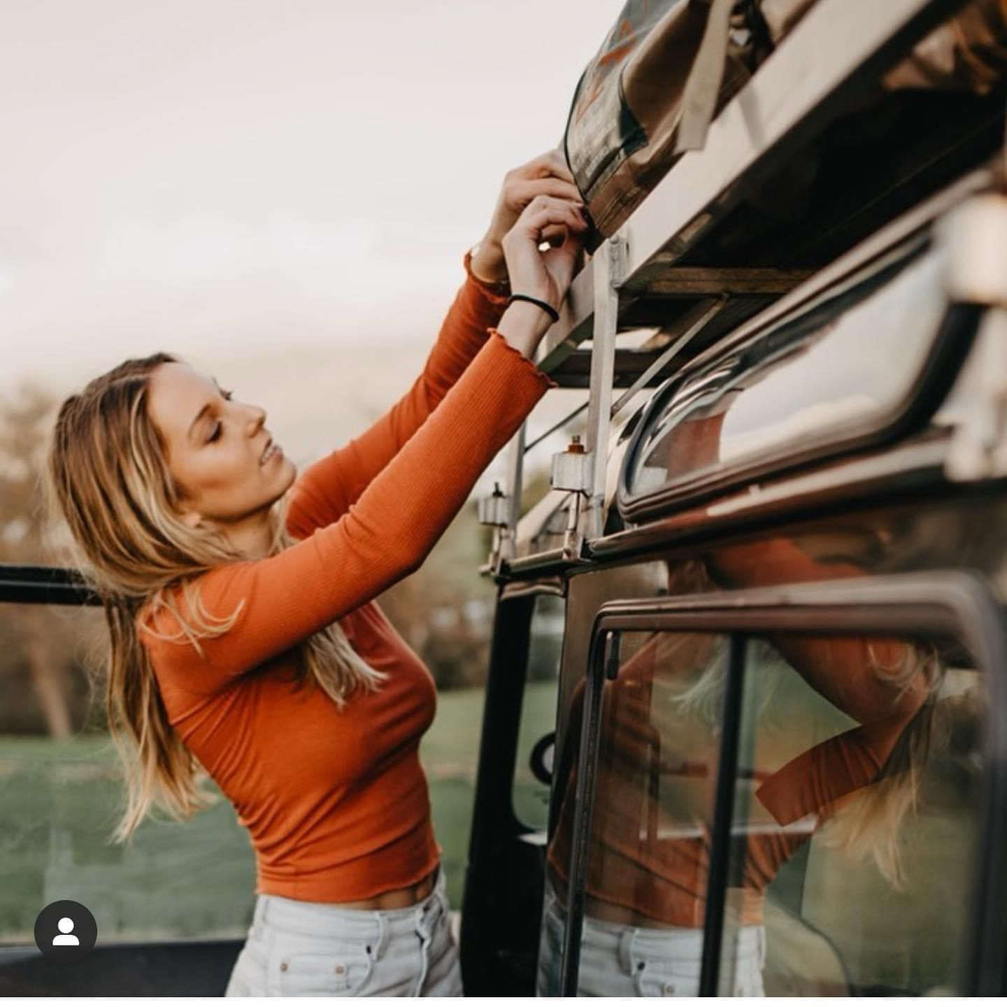 Woman securing gear on green Defender roof rack
