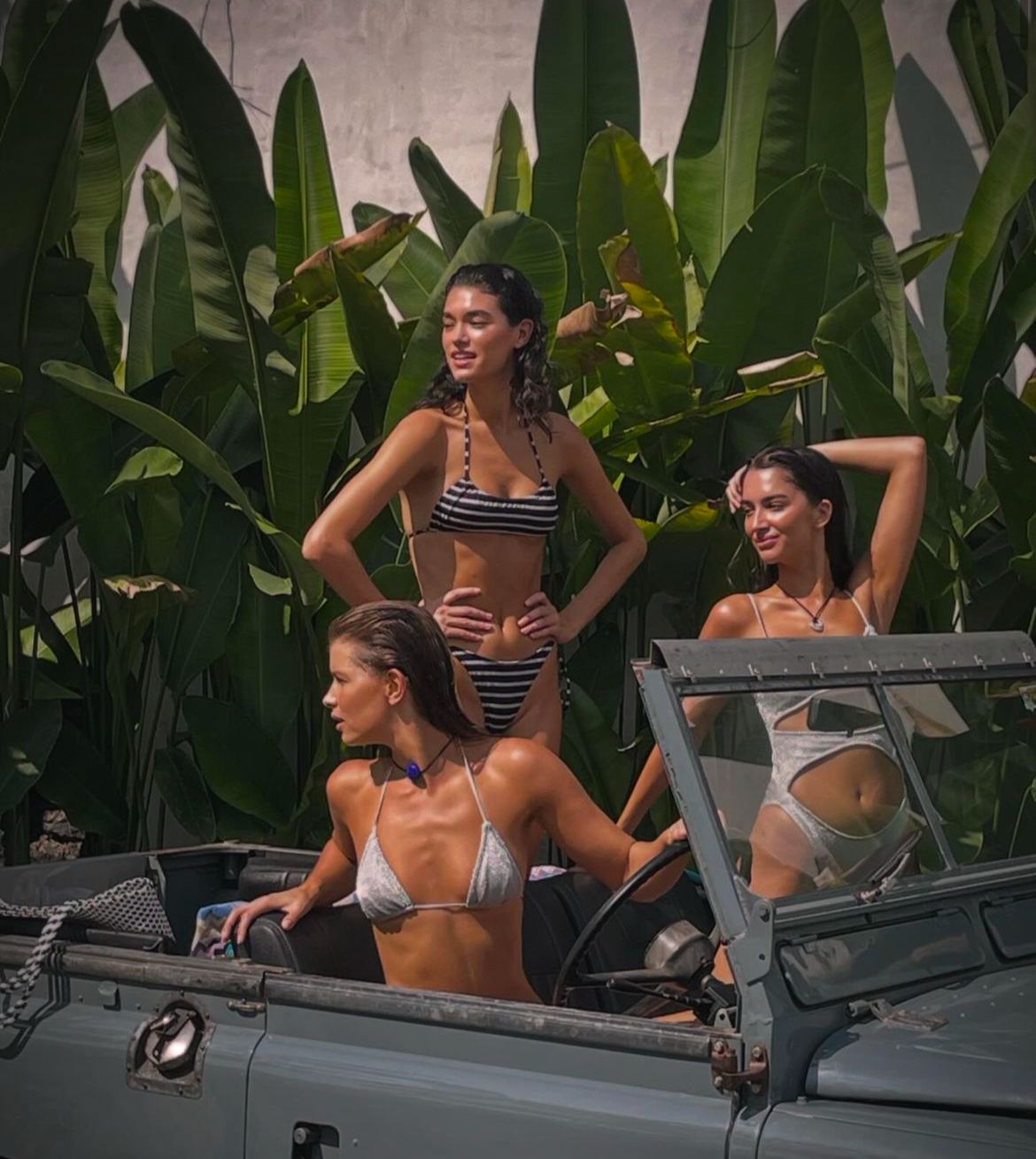 Blue Defender 90 soft top with three women, tropical backdrop