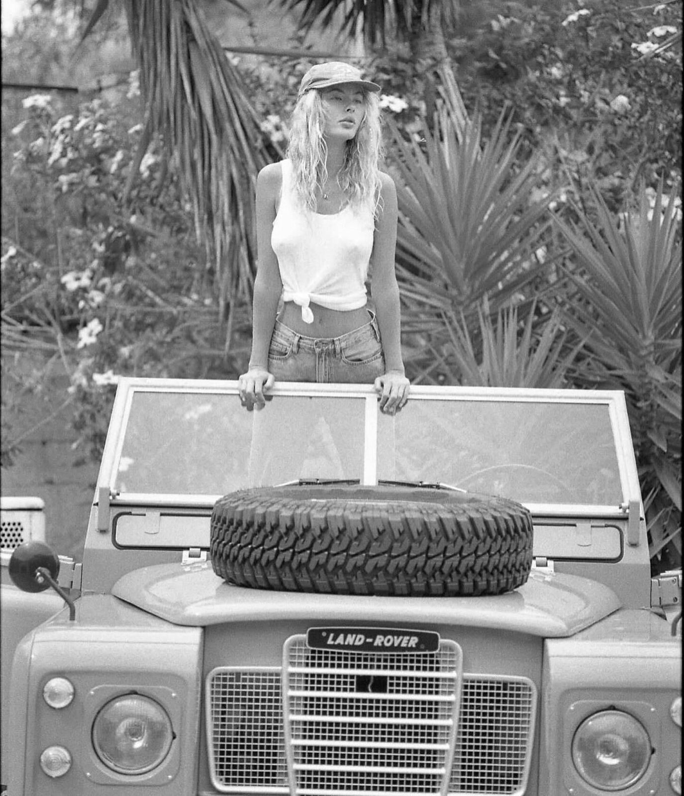 Black and white — woman with classic Land Rover in tropical setting