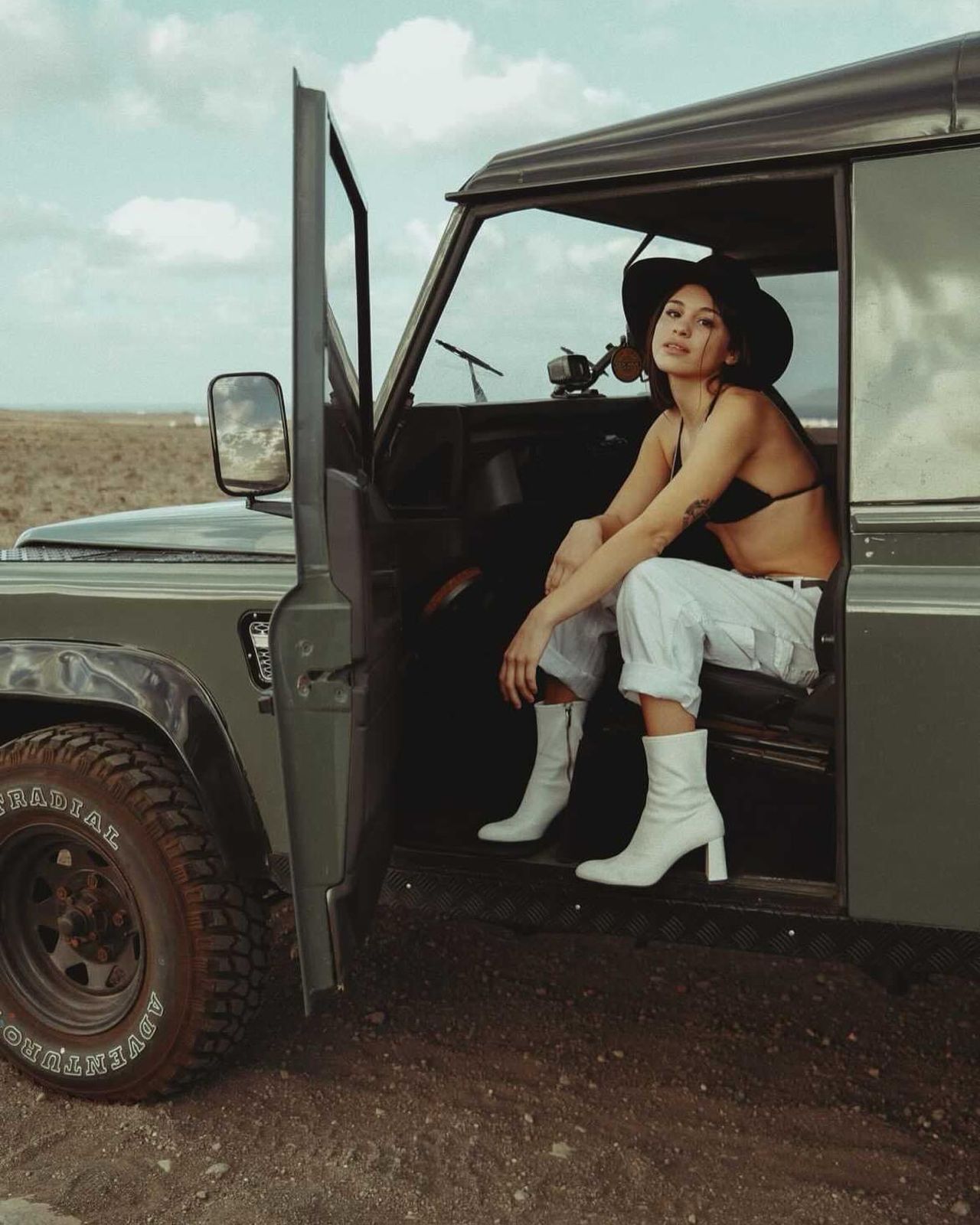 Woman in olive green Defender in desert
