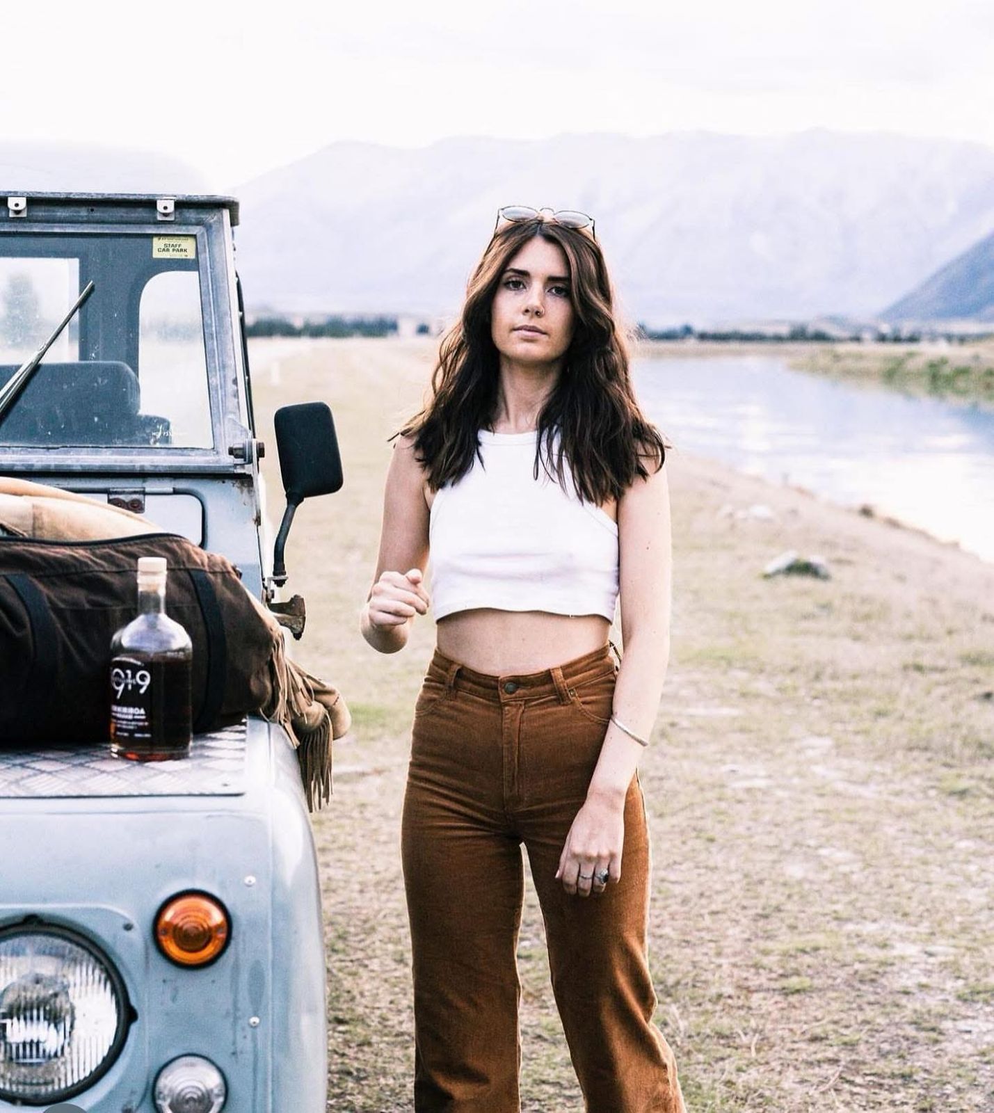 Light blue Defender with woman by lake and mountains