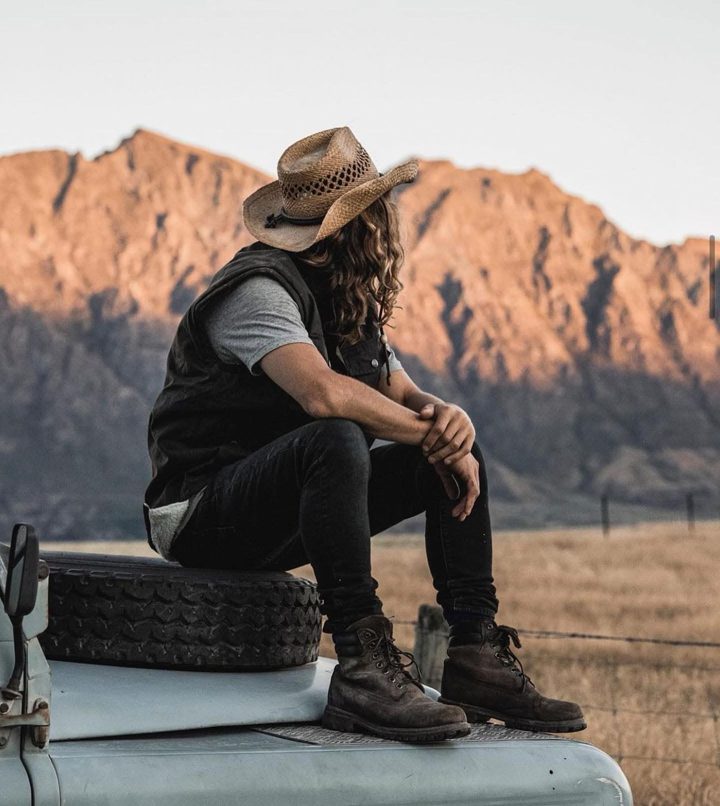 Heritage blue Defender with woman on hood at golden hour