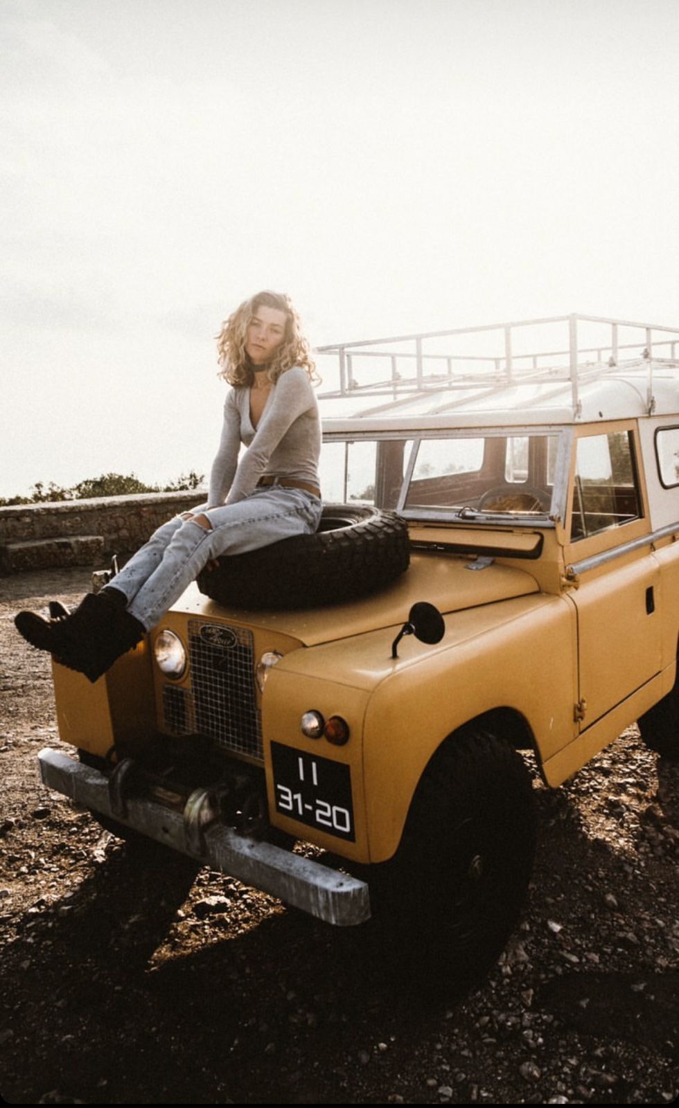 Mustard yellow classic Land Rover with woman on hood