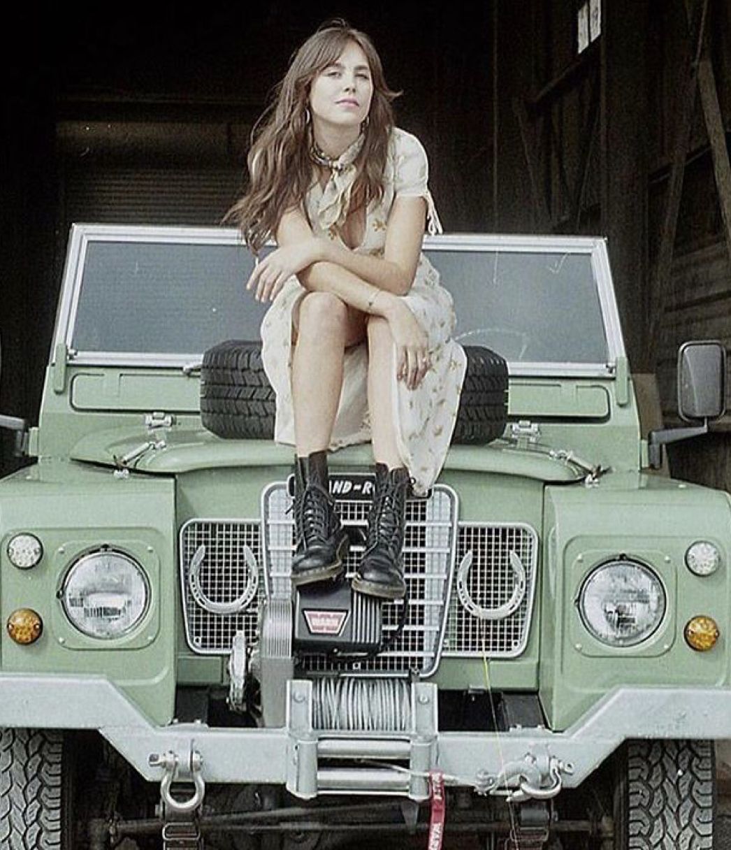 Sage green Defender with horseshoes on grille, woman on hood