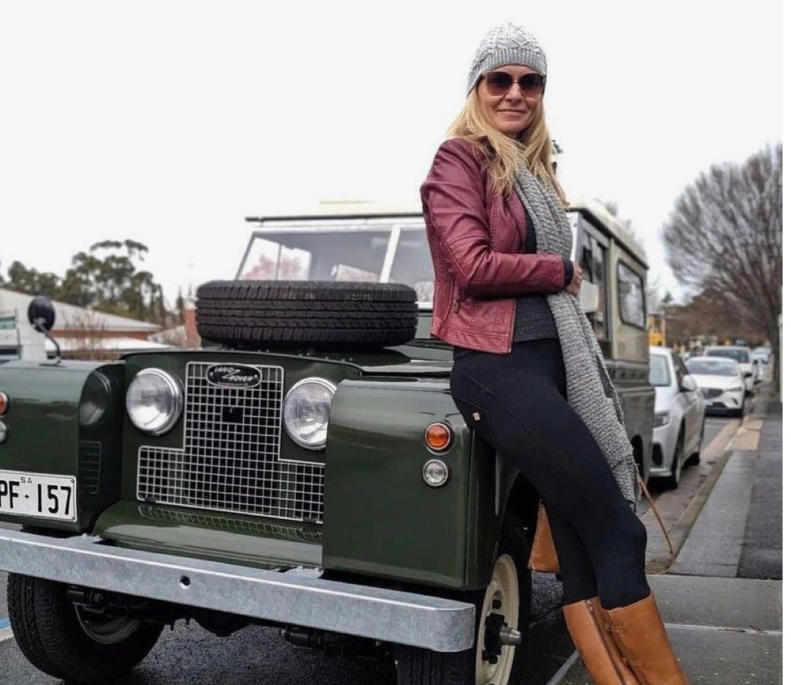 Dark green Series Land Rover on street with woman