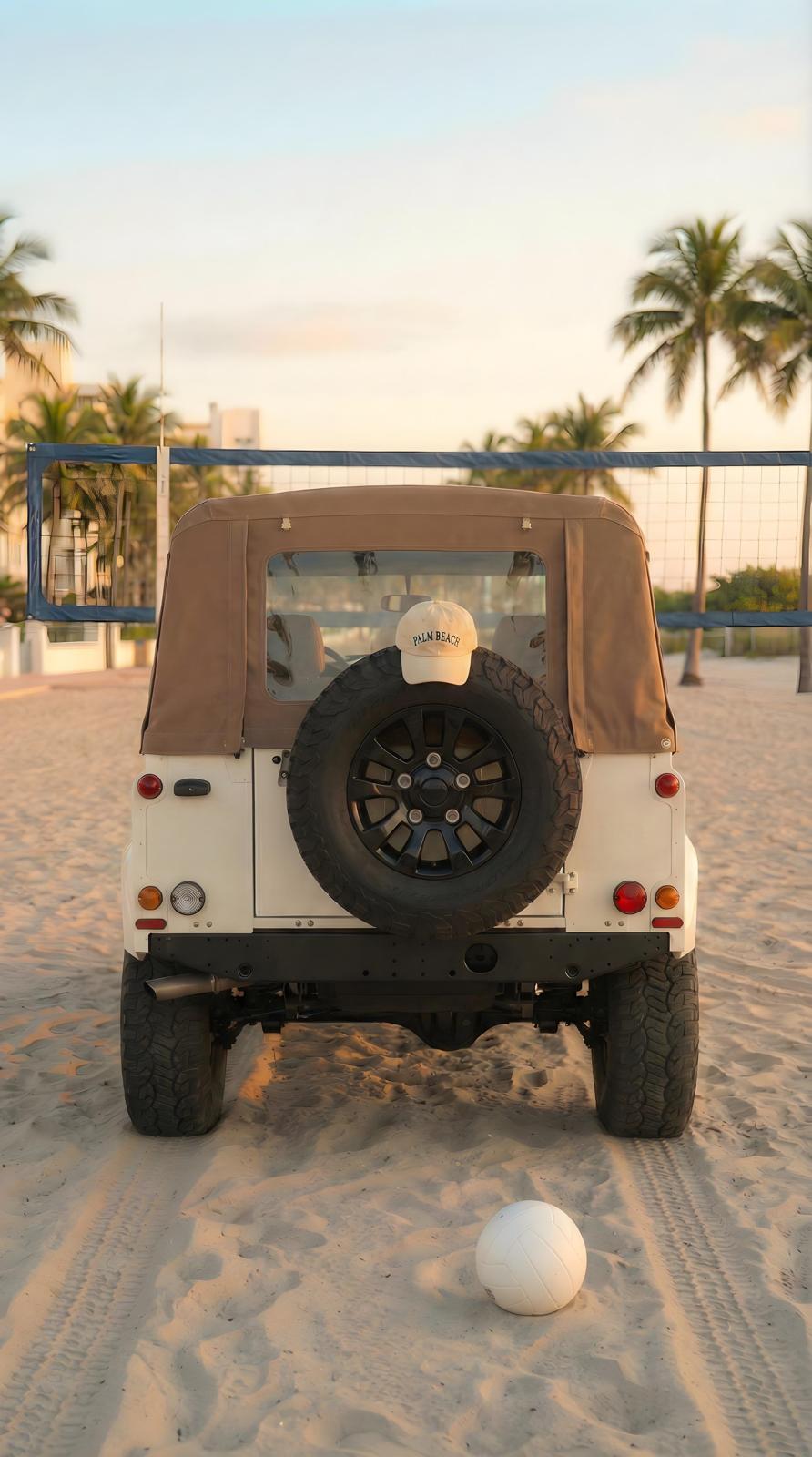White Defender 90 on beach at sunset, rear view